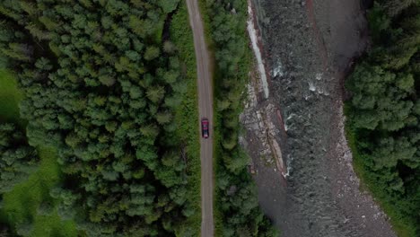vista aérea del coche aparcado en la carretera a lo largo del río que fluye a través del bosque