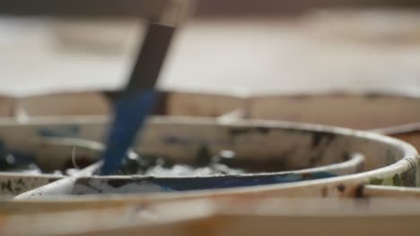 dipping brush into paint on artist painting palette, close up