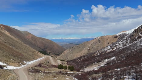 aerial winding dirt road through andes mountain landscape on sunny day, cerro la hoya, esquel, argentina