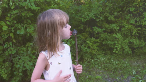 cute little girl tastes a burnt marshmallow on a stick