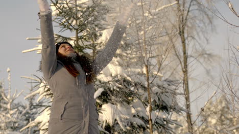 Slow-motion-shot-of-a-happy-woman-in-winter-clothes-throwing-handful-of-snow-enjoying-wintertime-on-a-sunny-morning