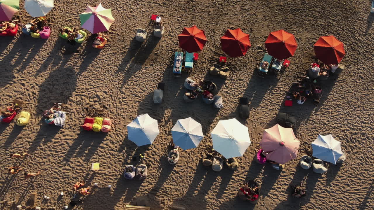 Beach scene with people relaxing under umbrellas
