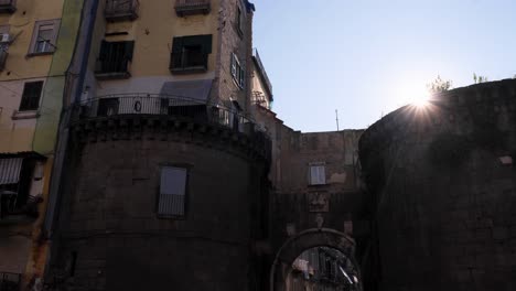 sunflares appear during tracking wide shot of old city gate and turrets in napoli italy