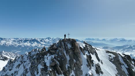 Una-Persona-De-Pie-En-Una-Cumbre-En-Los-Alpes-En-Un-Soleado-Día-De-Invierno