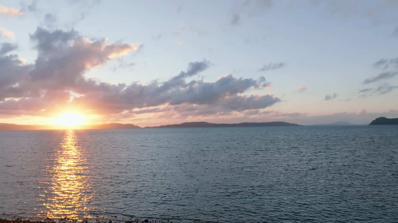 Drone turning towards the sunrise over the ocean in the Whitsunday Islands, QLD, Australia