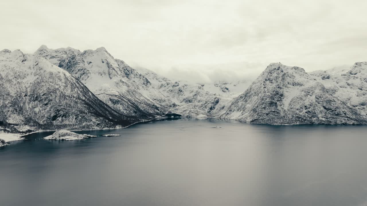 Snow-covered Mountains Around Calm Icy Fjord Under Overcast Sky In Arctic Landscape.Near Svolvaer, Norway. wide aerial shot