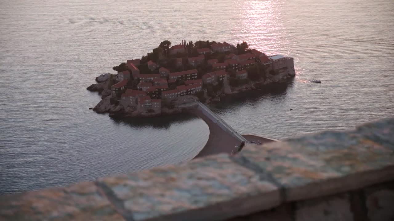 Solnedgang med utsikt over kystlinjen i Montenegro nær Sveti Stefan. Sakte filmavsløring av Sveti Stefan fra visningsplattformen over den.
