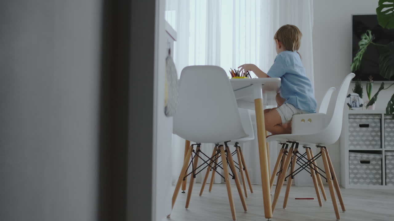 счастливая семья молодая красивая мать и двое сыновей рисуют цветными карандашами, сидя за столом на кухне. камера движется в замедленном движении