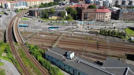 Vista-Aérea-Sobre-Los-Rieles-Que-Van-A-La-Estación-Central-De-Gotemburgo-Con-Tranvías-Y-Transporte-Público