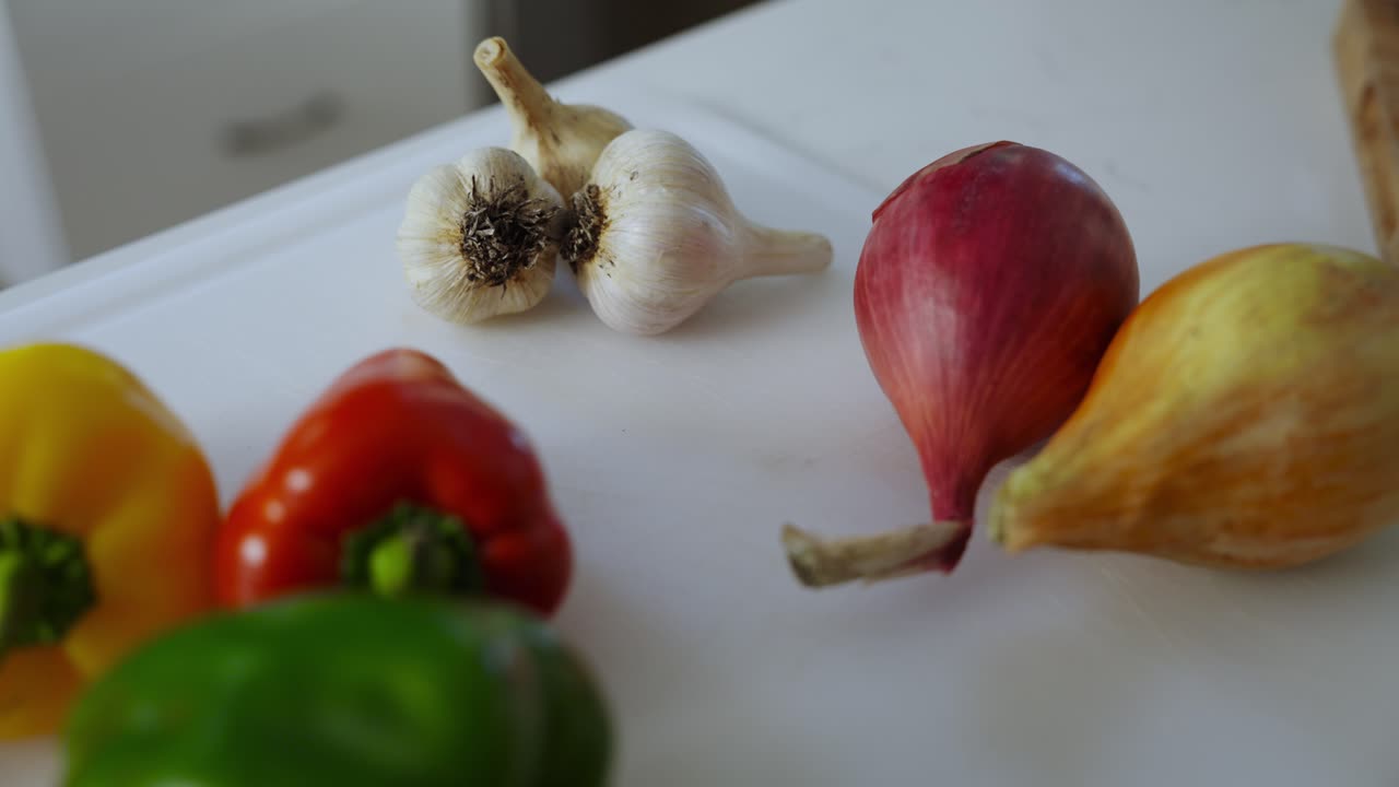 Colorful bellpapers and garlics kept on kitchen table. Closeup view.