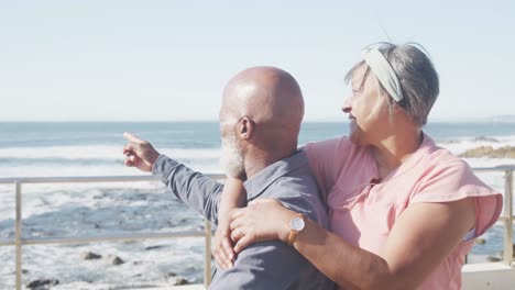 Portrait-of-happy-senior-african-american-couple-embracing-on-promenade-by-the-sea,-slow-motion