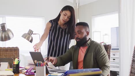 Diverse-male-and-female-friends-using-laptop-and-talking,-working-at-home-in-slow-motion