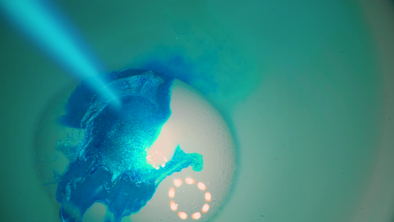 lasciando cadere un colore blu brillante su un uovo di gallina in acqua limpida