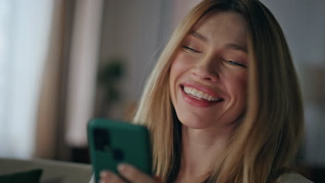 closeup laughing girl messaging by smartphone at home. woman reading cellphone