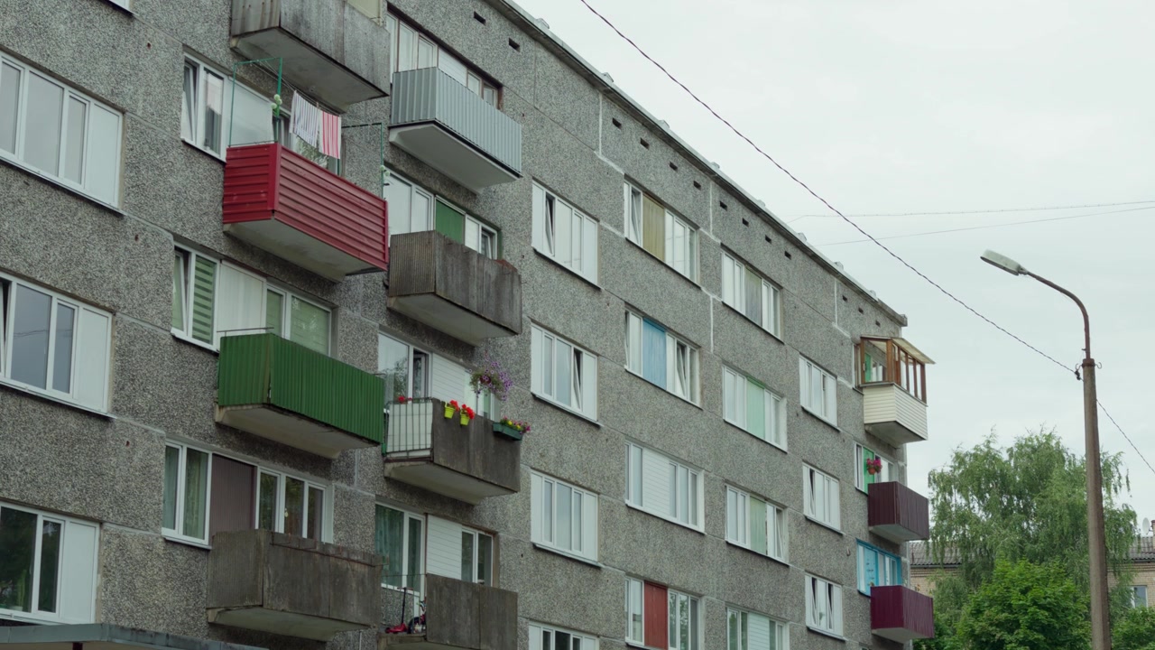 Vinkelutsikt opp mot en betongpanelblokk fra sovjettiden med fargerikt malte balkonger og vinduer i Daugavpils, Latvia, under en overskyet sommerdag