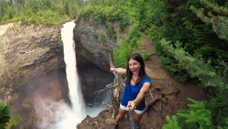 Woman-taking-a-selfie-against-the-waterfall-4k