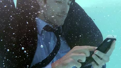 hombre de negocios usando teléfono inteligente bajo el agua