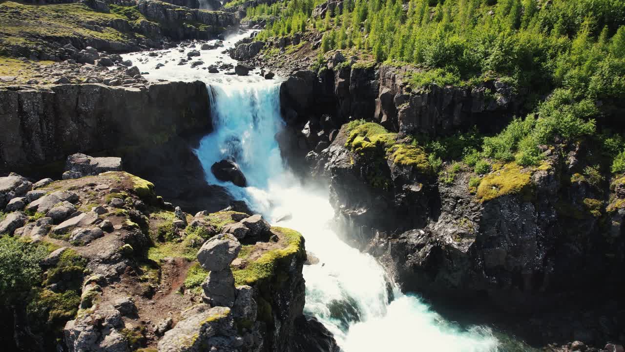 tiro de drone girando hacia arriba sobre una gran cascada con un arco iris y montañas en el fondo en islandia 4k