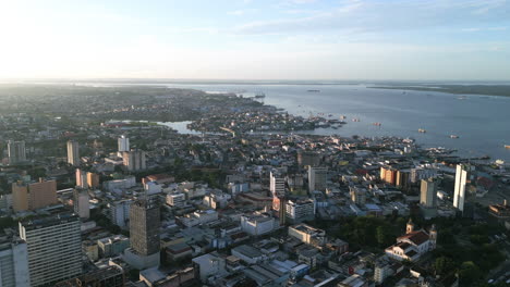sobrevuelo aéreo de los edificios del centro de manaus, brasil a la luz del amanecer con el río amazonas en el fondo