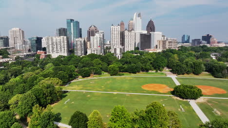 aerial sliding reveal of sports fields in park and tall midtown skyscrapers in background