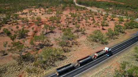 Vista-Aérea-Del-Tren-De-Carretera-De-Tres-Remolques-Con-Carga-Vacía-Conduciendo-En-Carretera-Asfaltada-En-Qld,-Australia