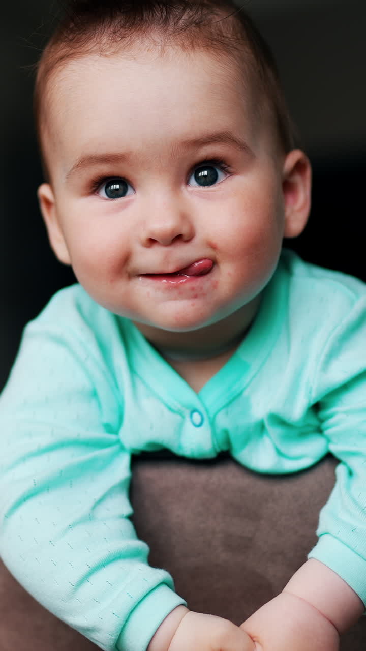 A baby with a green shirt is looking at the camera