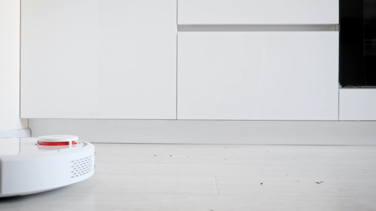 Close-up of a robot vacuum cleaner picking up trash from the floor, side view
