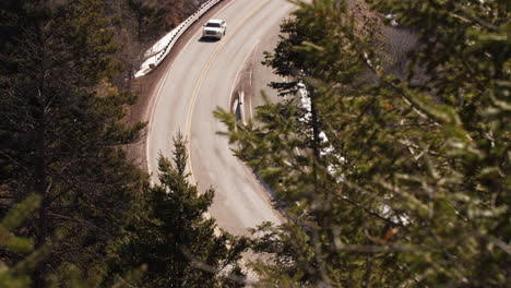 a truck drives along a winding mountain road in the forest, long lens