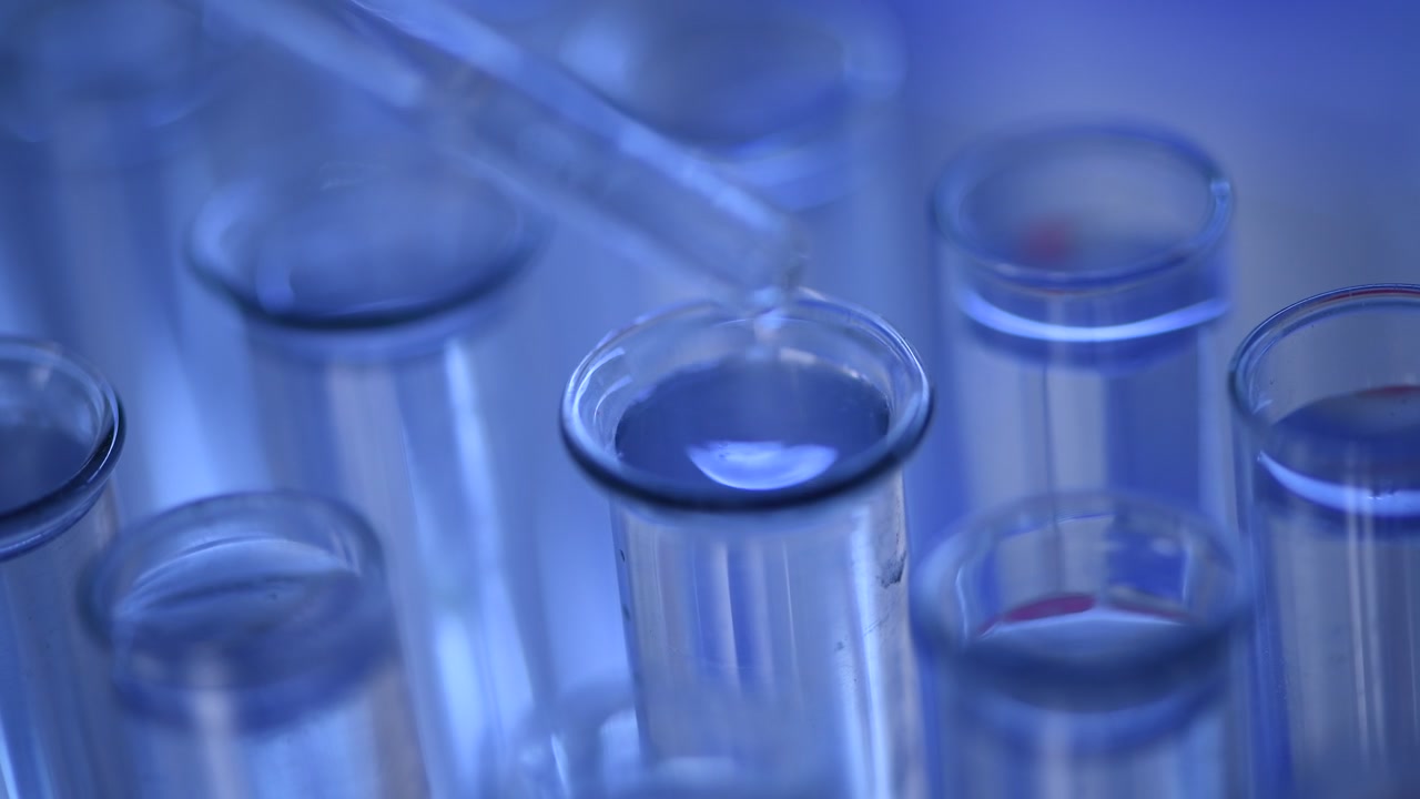 Pipette Dropping Blue Liquid into a Test Tube in a Laboratory