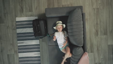 bored preschooler plays with sunglasses resting on couch