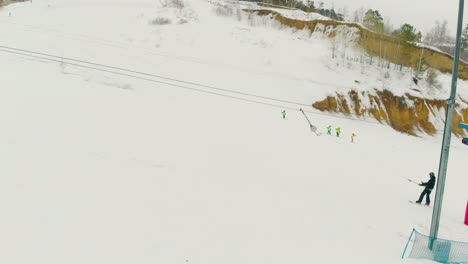 skier on skies rises on snowy hill by t-bar lift aerial view