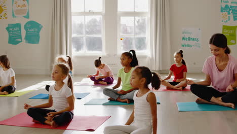 children and instructor practicing yoga in a bright studio