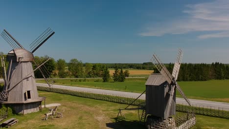 aerial shot flying between two wooden mills, one of them with their blades moving