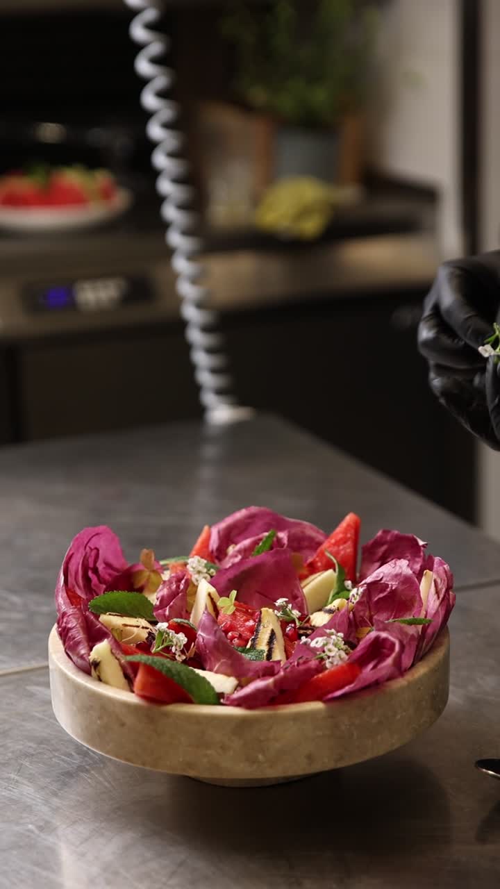 Chef che guarnisce un'insalata fresca di radicchio e anguria in una cucina professionale
