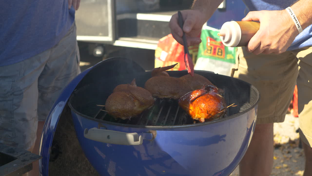 A man glazes BBQ chicken at a BBQ Cookoff.