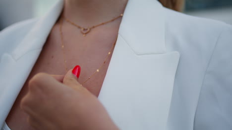 woman hand touching jewelry on neck close up. female fingers playing pendant.