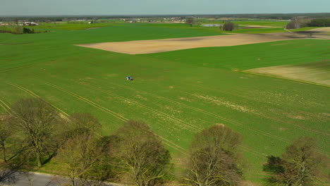 vista aérea de extensos campos verdes con un solo tractor visible