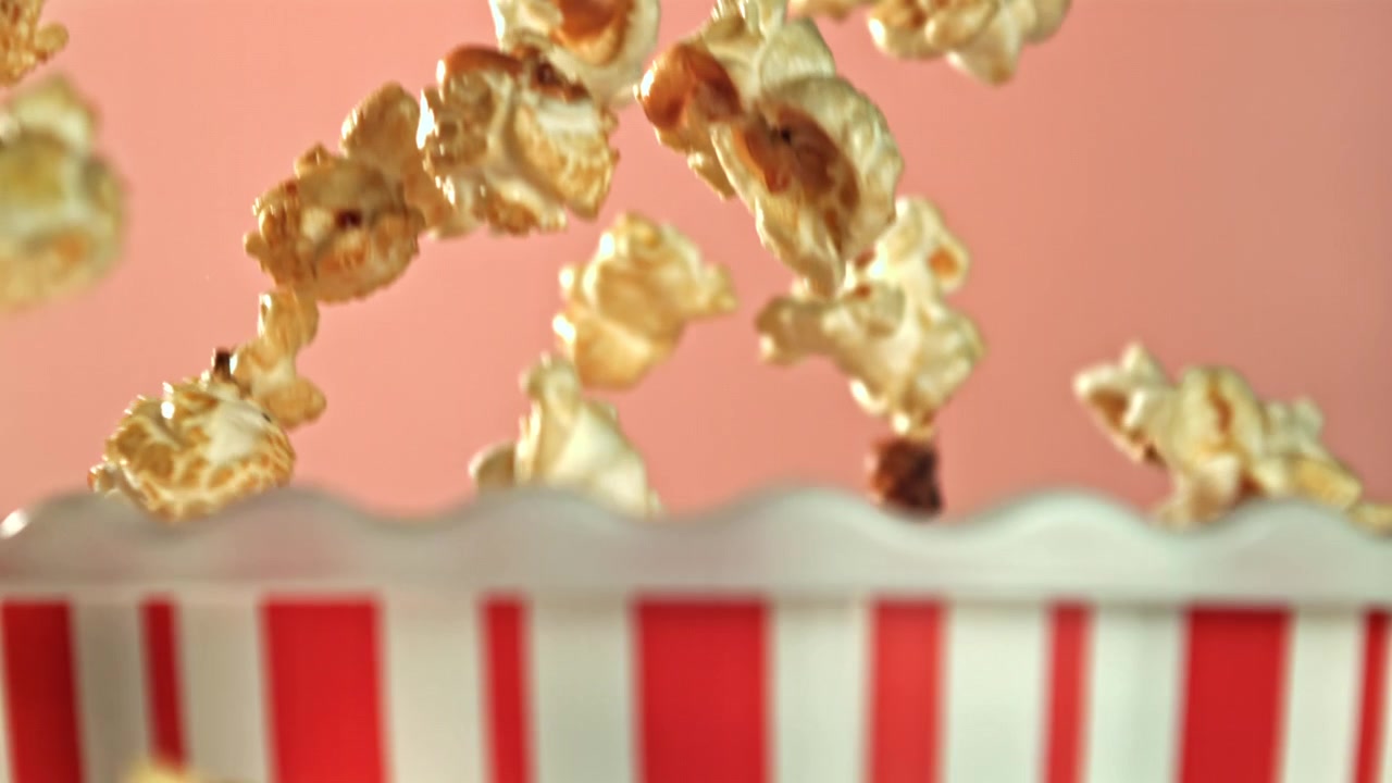 Popcorn che cadono al rallentatore in una scatola di popcorn a strisce