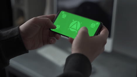 smartphone with horizontal green screen chroma. holding phone, watching, touching, typing, playing. mockup.