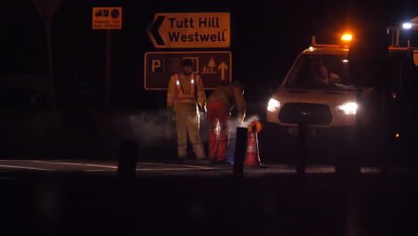 unrecognizable road workers line painting on a main road in the uk at night in slow motion