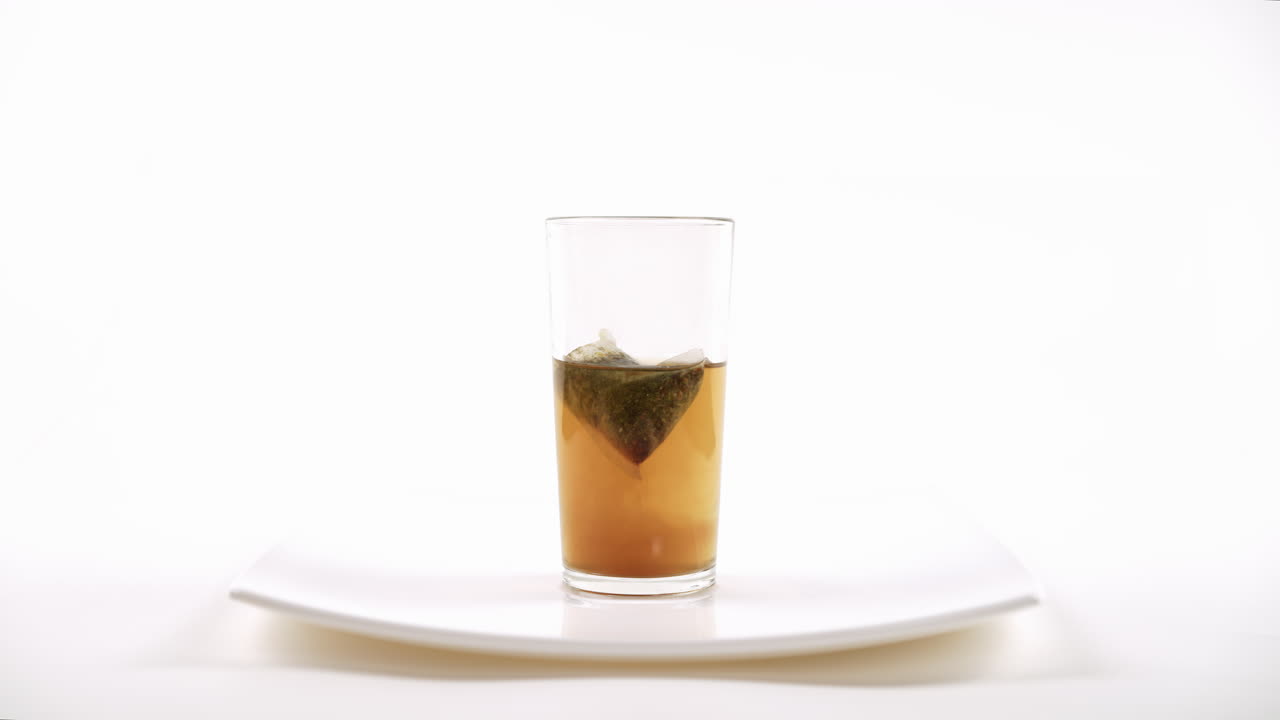 차 위에 은 유리잔에 뜨거운 물을 담은 차 봉투와 함께 진행 중인 차 주입