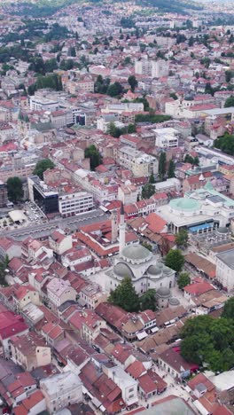 historic mosque and minaret surrounded by sarajevo rooftops and streets, vertical shot