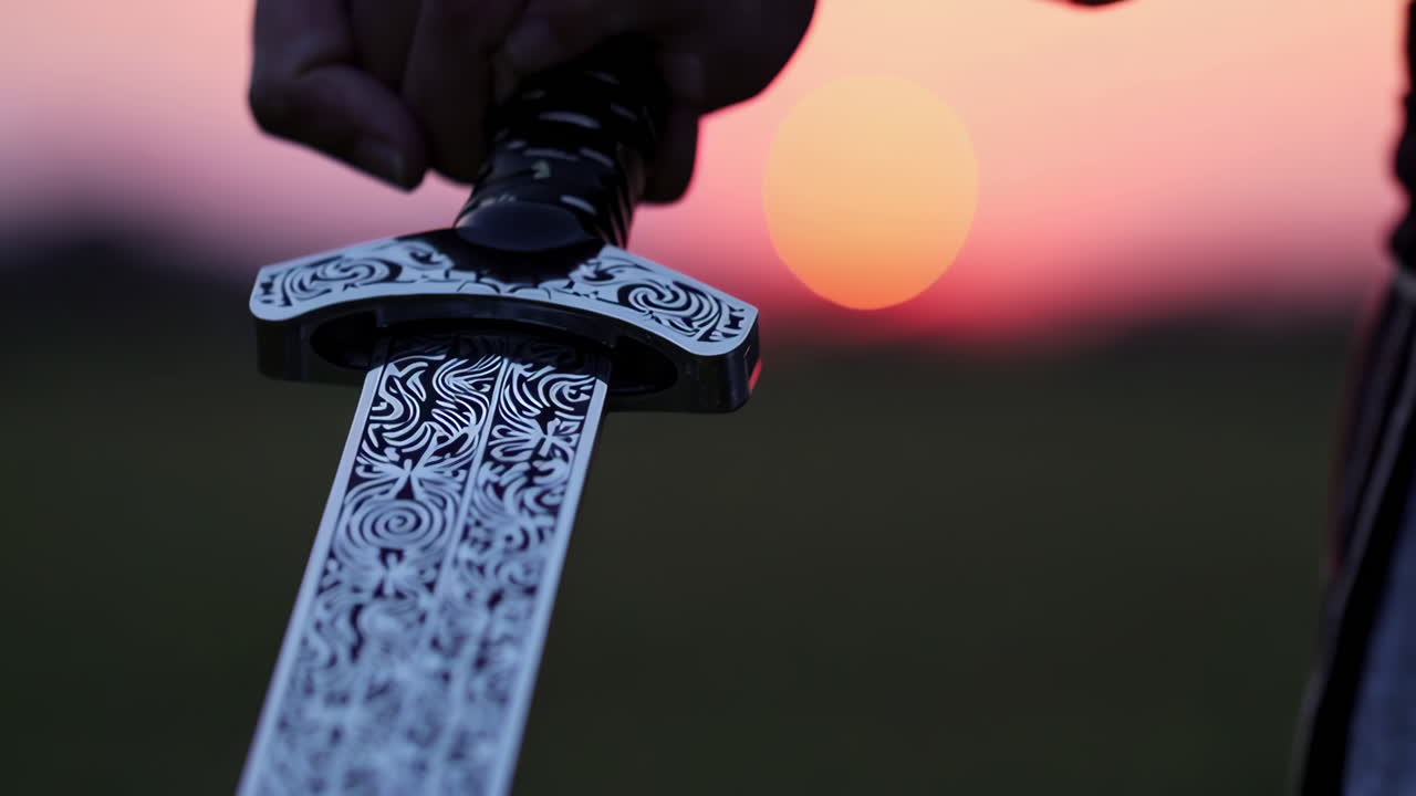 Person Holding Ornate Sword at Sunset