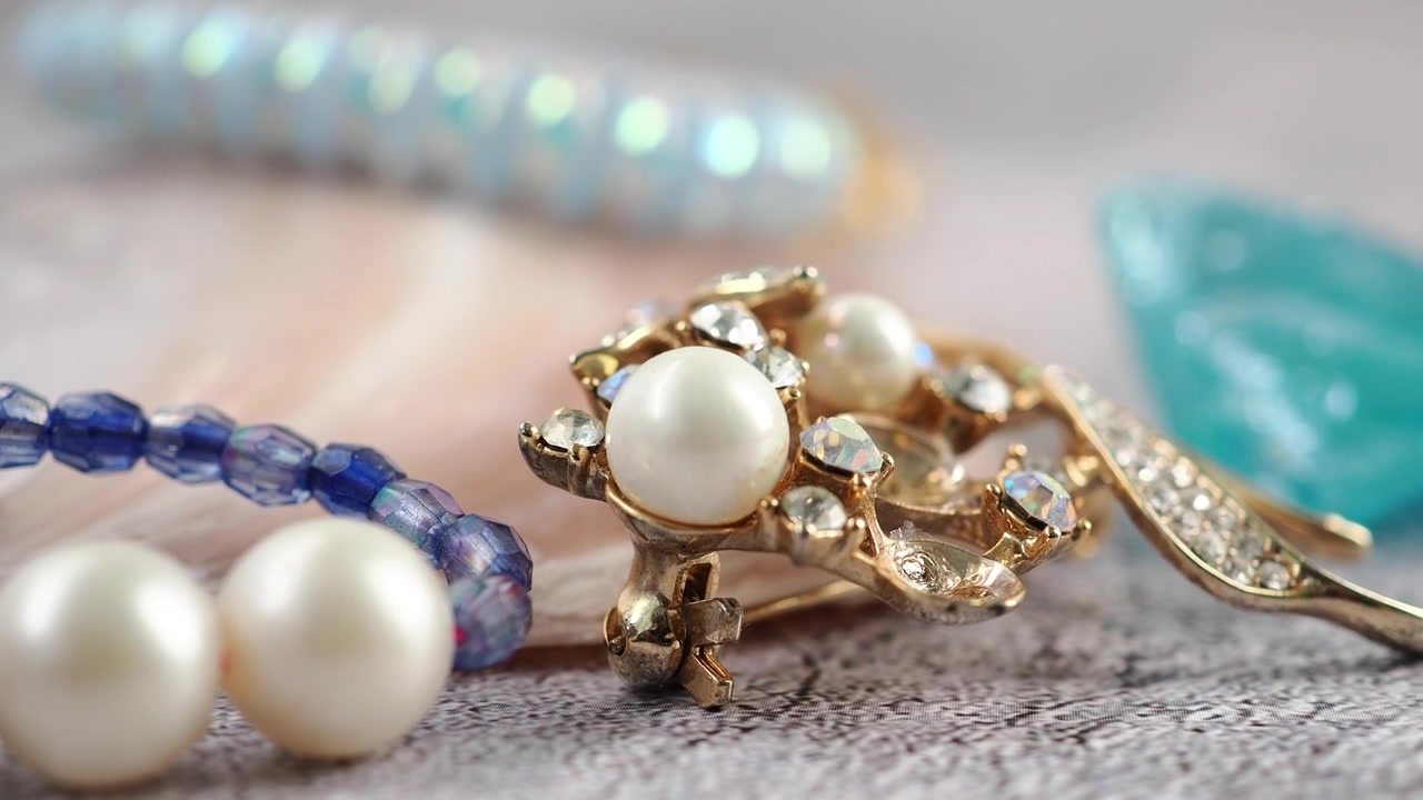 Primo piano di una spilla vintage d'oro con perle e strass.