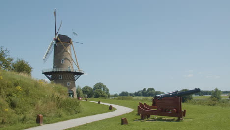 plano general de aspas de molino de viento tradicionales girando en el viento con viejos cañones en primer plano