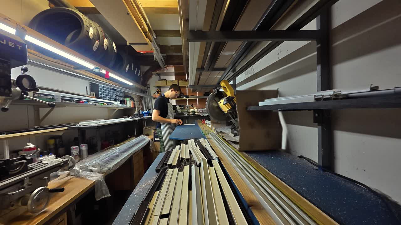 Timelapse of male carpenter cutting metal lengths with mitre saw to make blinds