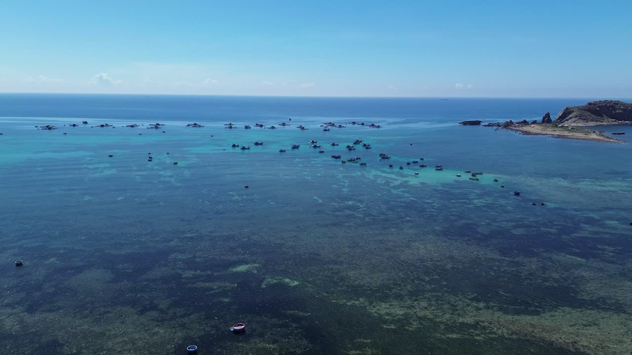 Aerial view of fishing village in Ninh Hải District, Ninh Thuận, featuring an ascending movement that showcases fishing boats amid the clear blue waters.