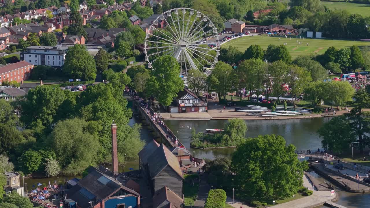 A scenic drone sweep of Stratford-upon-Avon, featuring the lush Bancroft Gardens, the winding River Avon, and the iconic giant Ferris wheel against a beautiful English landscape