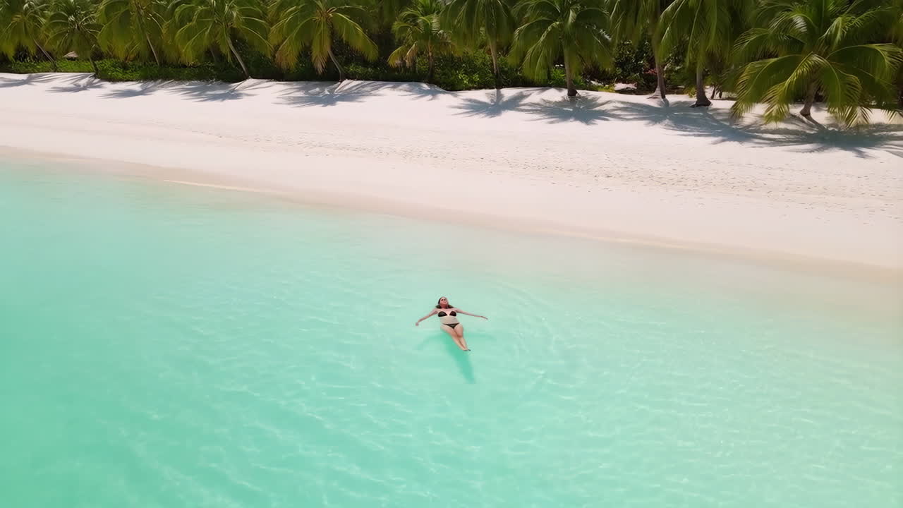 Woman Floating in Turquoise Water by a Tropical Beach