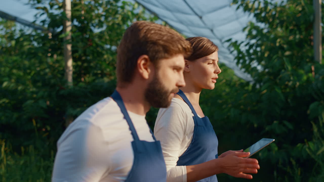 두 명의 농업 소유자가 디지털 태블릿 패드를 사용하여 데이터를 연구하고 있습니다.